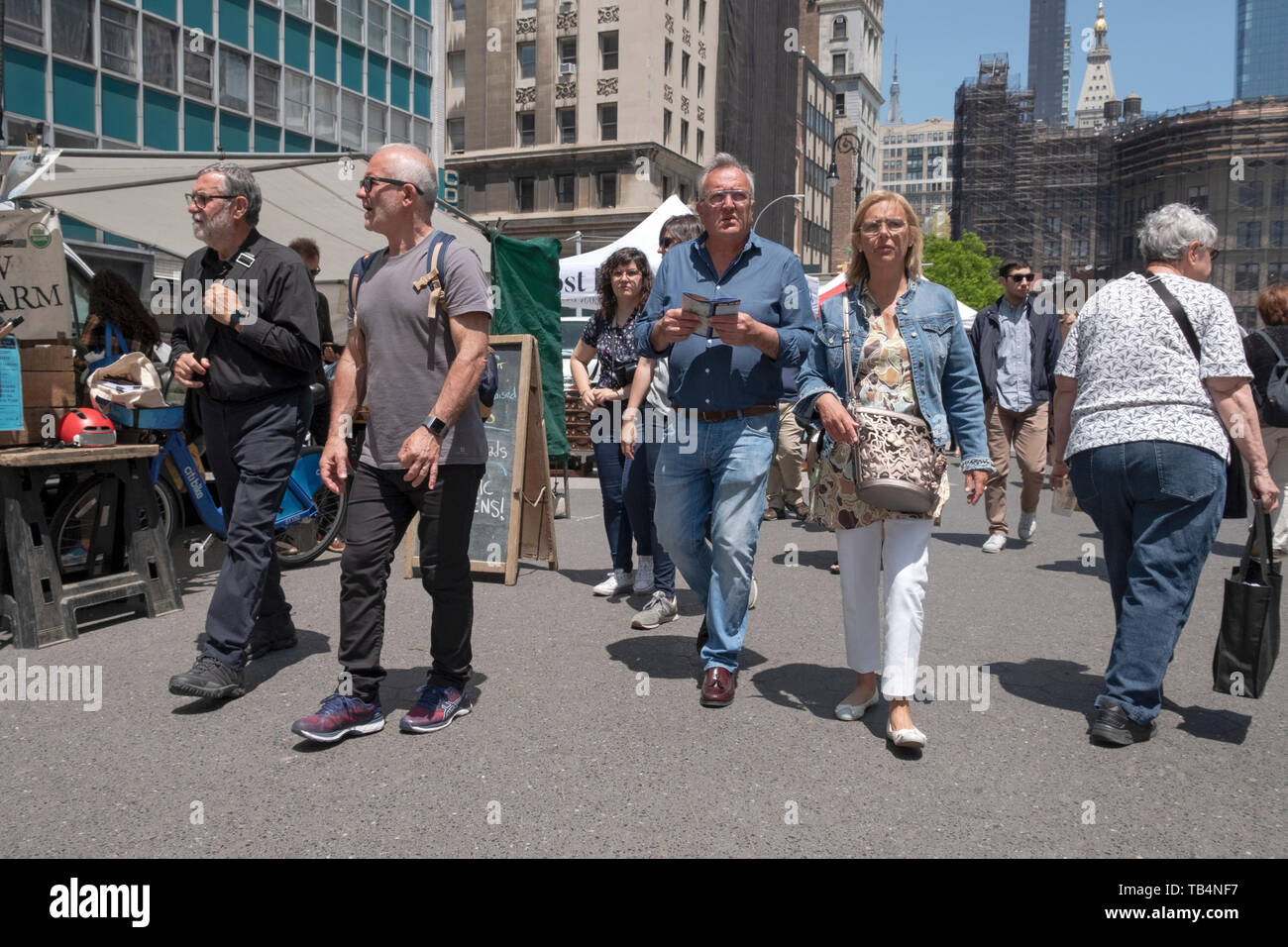 Un centro turistico di età matura a piedi attraverso la Piazza Unione Mercato verde in possesso di una mappa. A Manhattan, New York City. Foto Stock