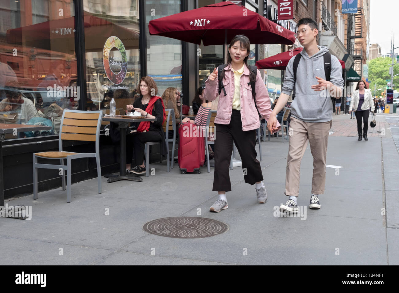 Una giovane coppia asiatica a piedi su Broadway in Greenwich Village e si impegnano in animata conversazione. Manhattan, New York City. Foto Stock