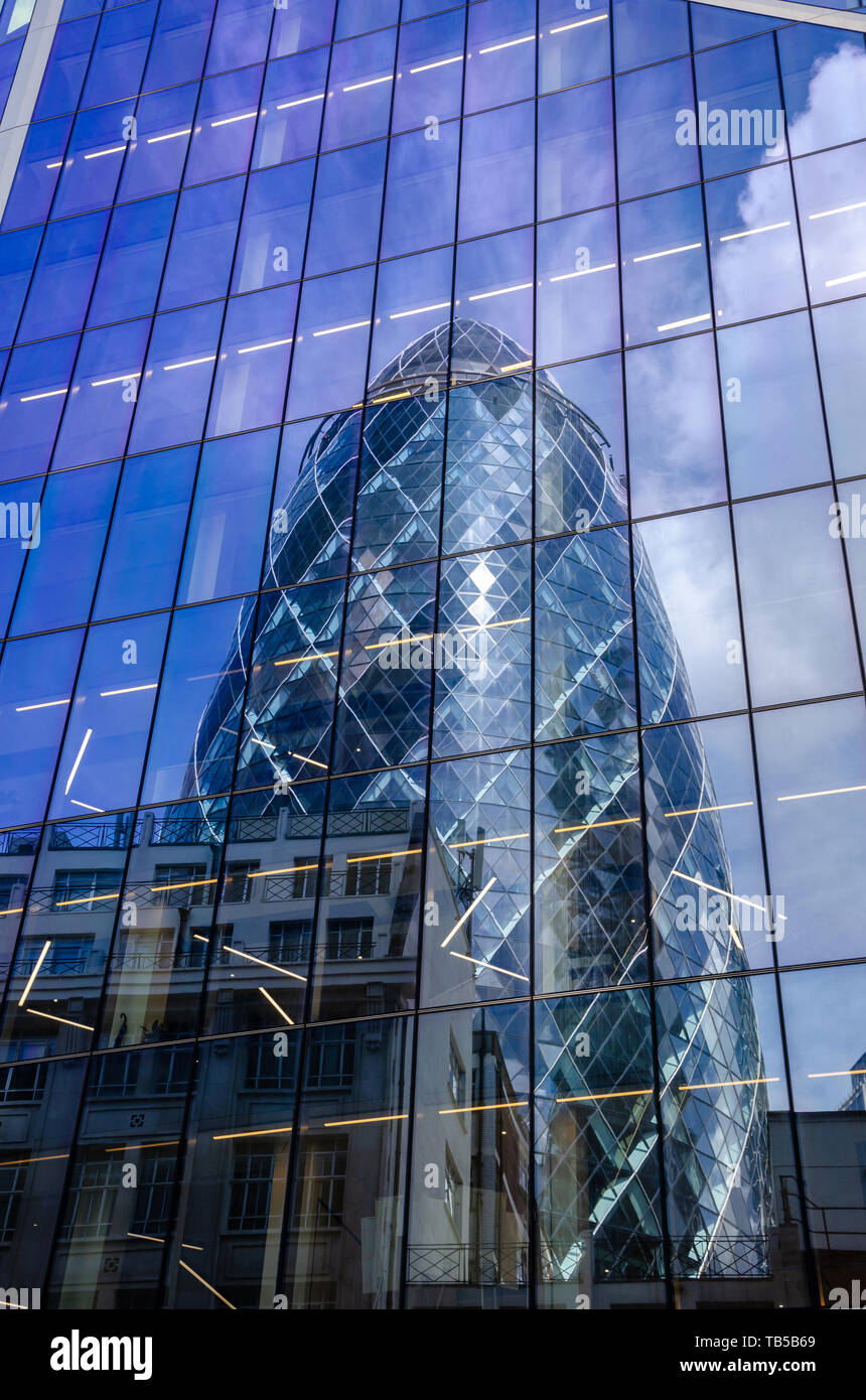 Il Gherkin è visto in una riflessione int egli lato del bisturi nel quartiere finanziario della City di Londra, Regno Unito Foto Stock