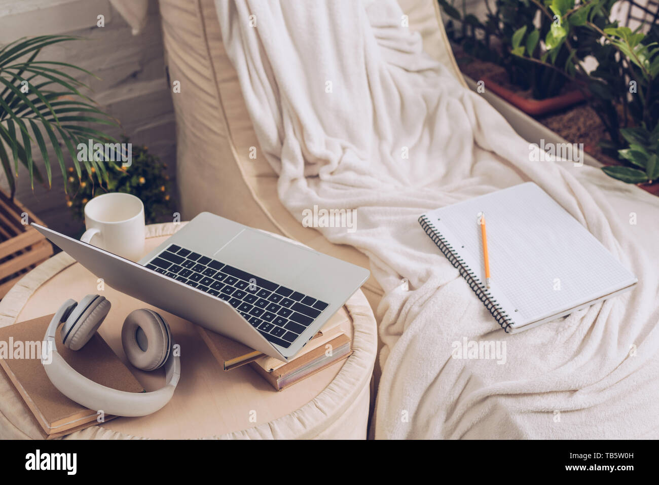 Laptop, cuffie, libri e tazza di caffè sul pouf vicino soft chaise lounge Foto Stock