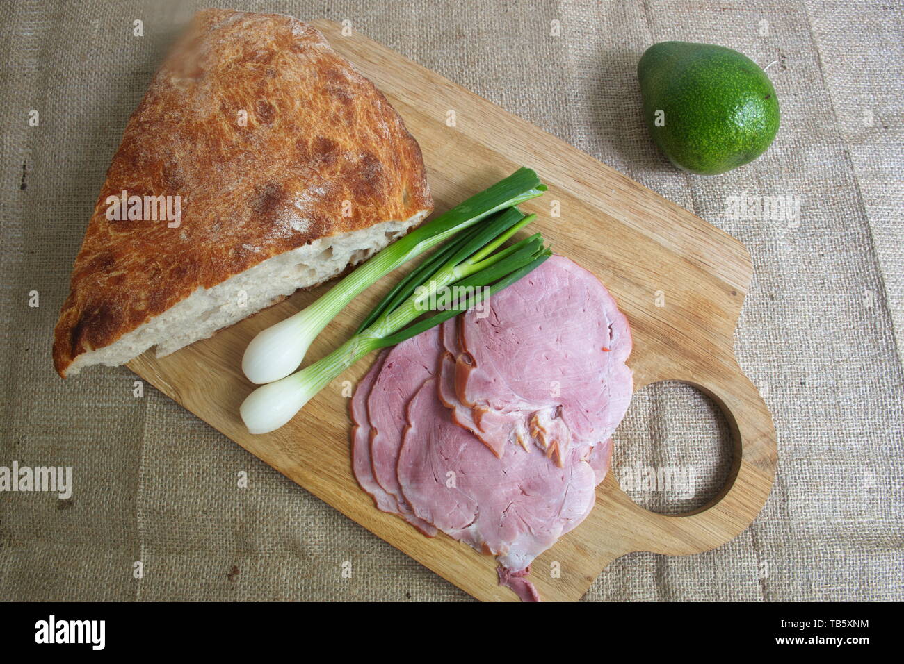 Direttamente sopra il colpo di pane, prosciutto cotto, cipolla e di avocado sul bordo di taglio Foto Stock