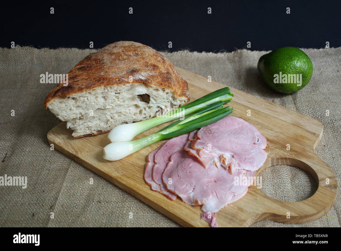 Elevato angolo di visione del pane, prosciutto cotto, cipolla e di avocado sul bordo di taglio Foto Stock