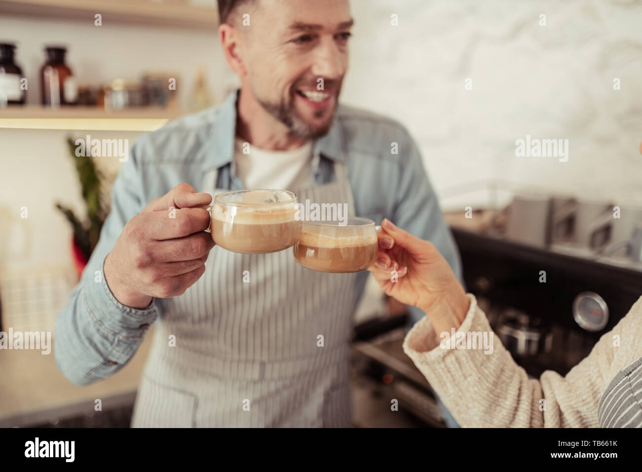 Chin-mento. Felice l'uomo in piedi vicino alla macchina da caffè cembalo che bicchieri di caffè insieme con sua moglie. Foto Stock