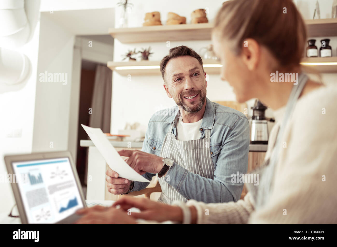 La condivisione di pensieri. Bel uomo sorridente a sua moglie puntando su un foglio di carta mentre si lavora insieme. Foto Stock