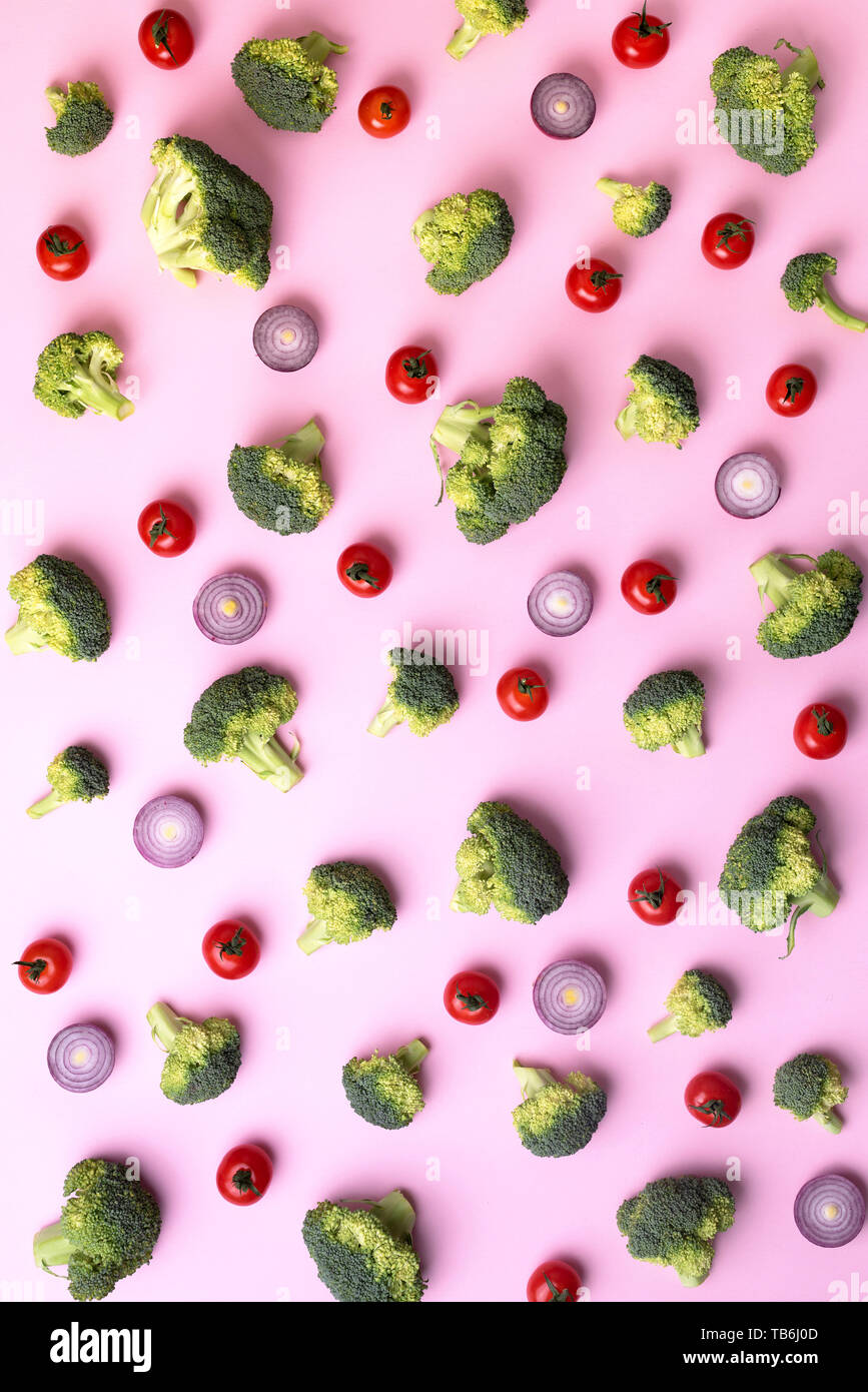 Layout creativi di broccoli verdi, pomodori e cipolla rosa su sfondo della carta. Vista dall'alto. Modello di cibo in stile minimal Foto Stock