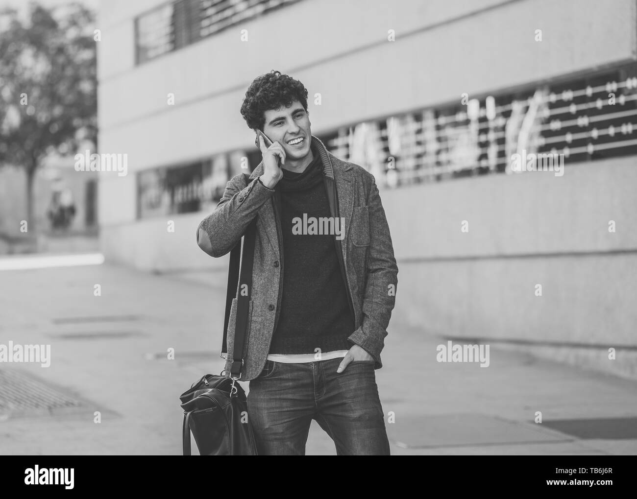 Giovane uomo attraente nel suo ventenne felice di parlare e chattare con gli amici su social media su smart phone sono in vacanza in Europa. In Comunicazione, te Foto Stock