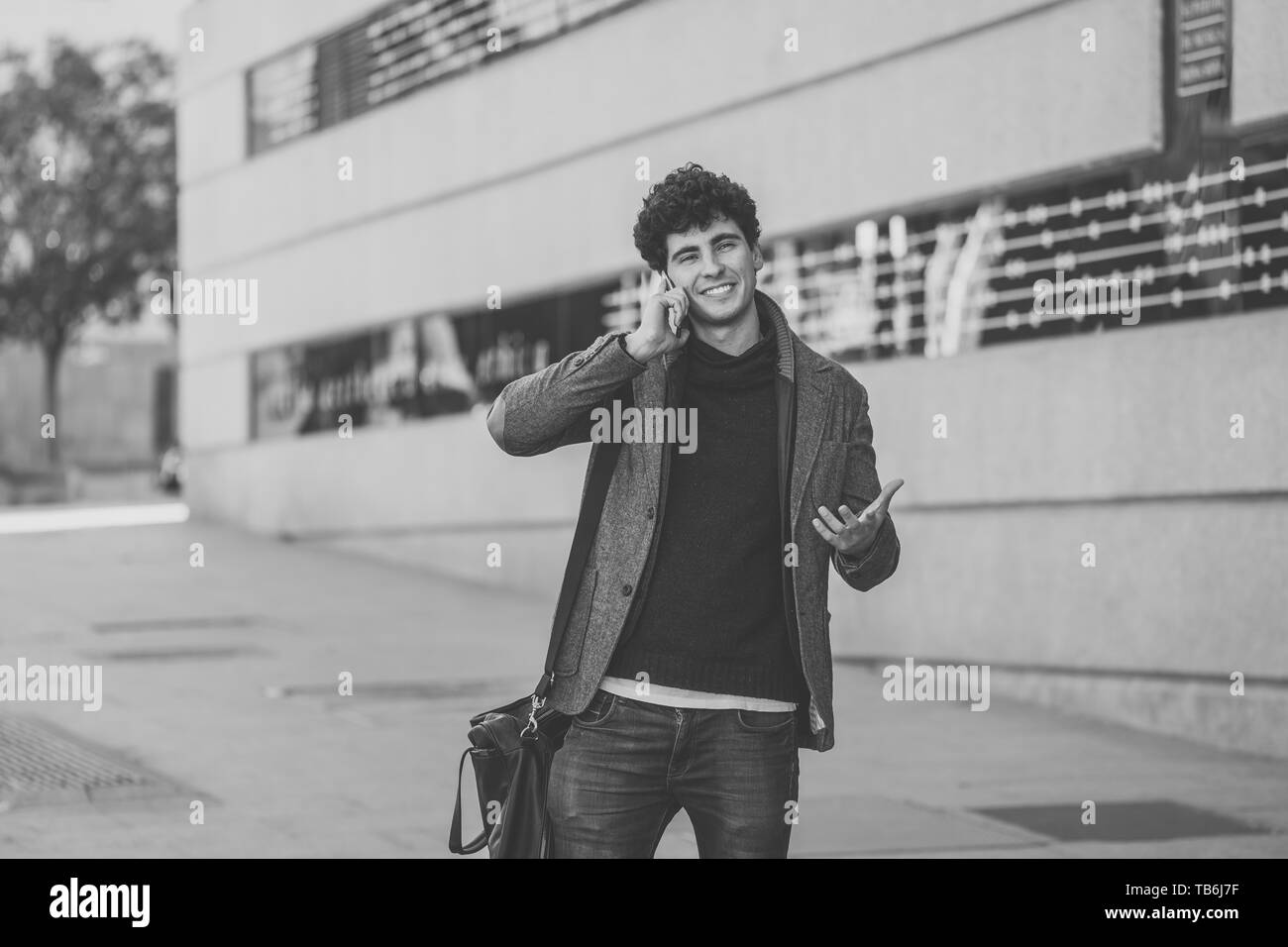 Giovane uomo attraente nel suo ventenne felice di parlare e chattare con gli amici su social media su smart phone sono in vacanza in Europa. In Comunicazione, te Foto Stock