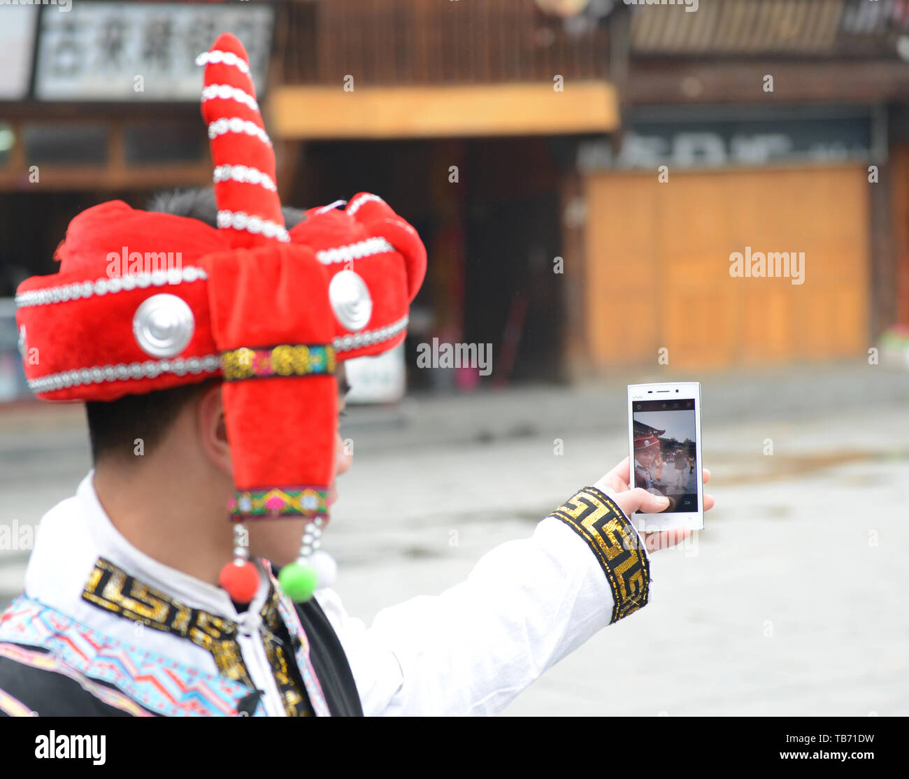Un Cinese turistica prendendo il suo selfie nel villaggio di Xinjiang, Guizhou, Cina. Foto Stock