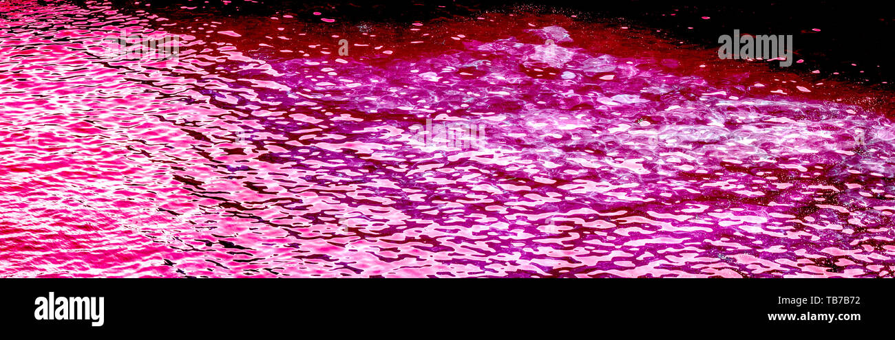 Foto orizzontale di acqua in rosa fucsia, colore magenta con luce solare riflettente. Foto Stock