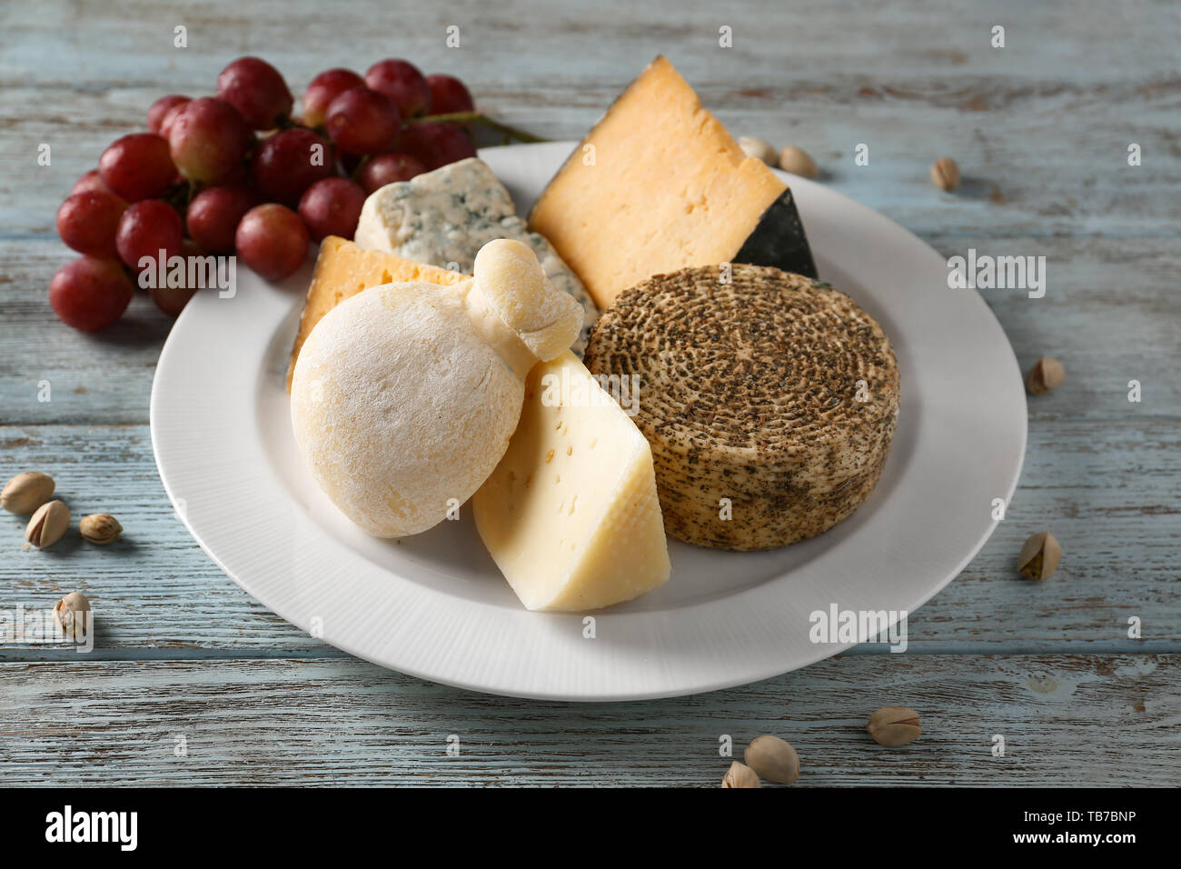 Piastra con assortimento di formaggi saporiti sul tavolo di legno Foto Stock
