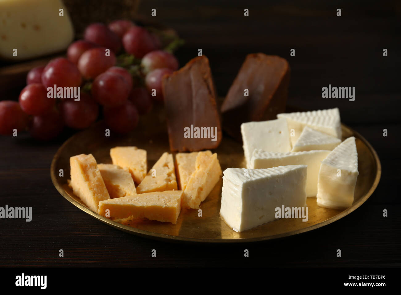 Piastra con assortimento di formaggi saporiti sul tavolo di legno Foto Stock