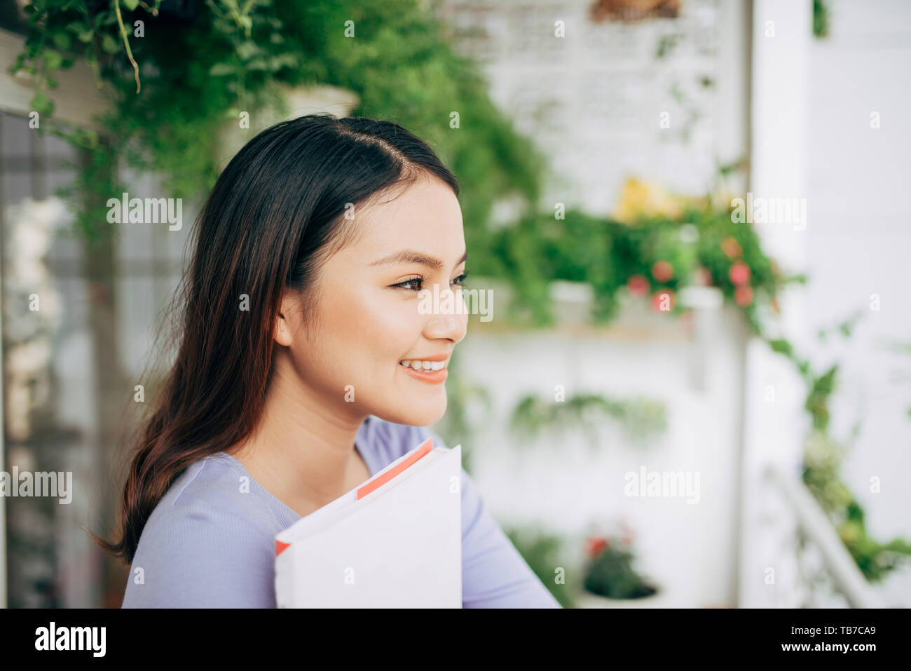 Giovane bella donna si siede e legge un libro su una terrazza Foto Stock