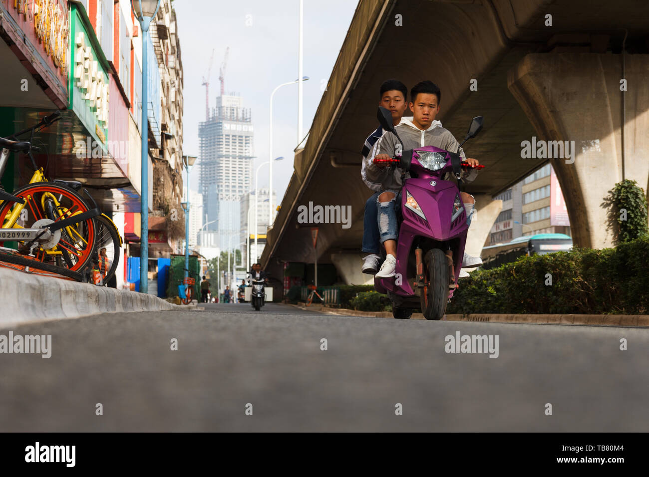 28 Luglio 2018- Kunming/Cina due uomini cavalcare un e-bike nella città cinese Foto Stock