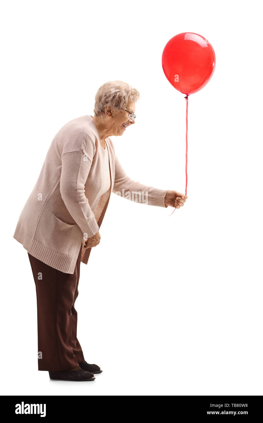 Lunghezza piena ripresa del profilo di una donna senior in possesso di un palloncino rosso isolato su sfondo bianco Foto Stock