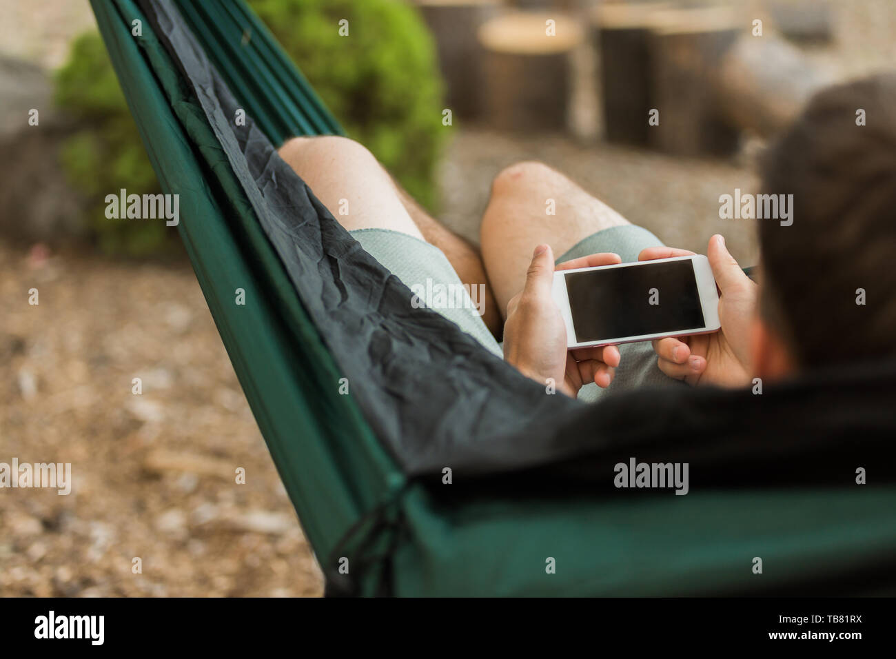 Concetto di ricezione internet sullo smartphone durante il campeggio in luogo remoto, il cellulare in amaca Foto Stock