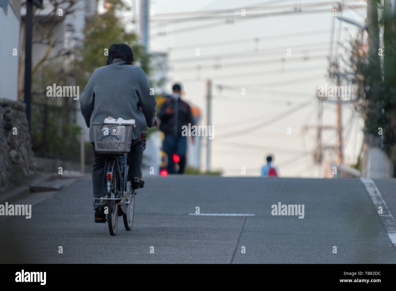 La gente nelle strade di Tokyo, una persona in bicicletta da soli dopo il tramonto. Foto Stock