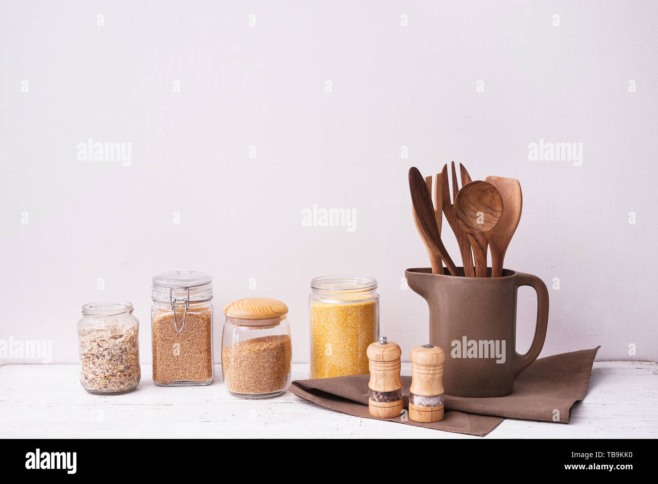 Set di utensili da cucina con semole sul tavolo vicino a muro bianco Foto Stock