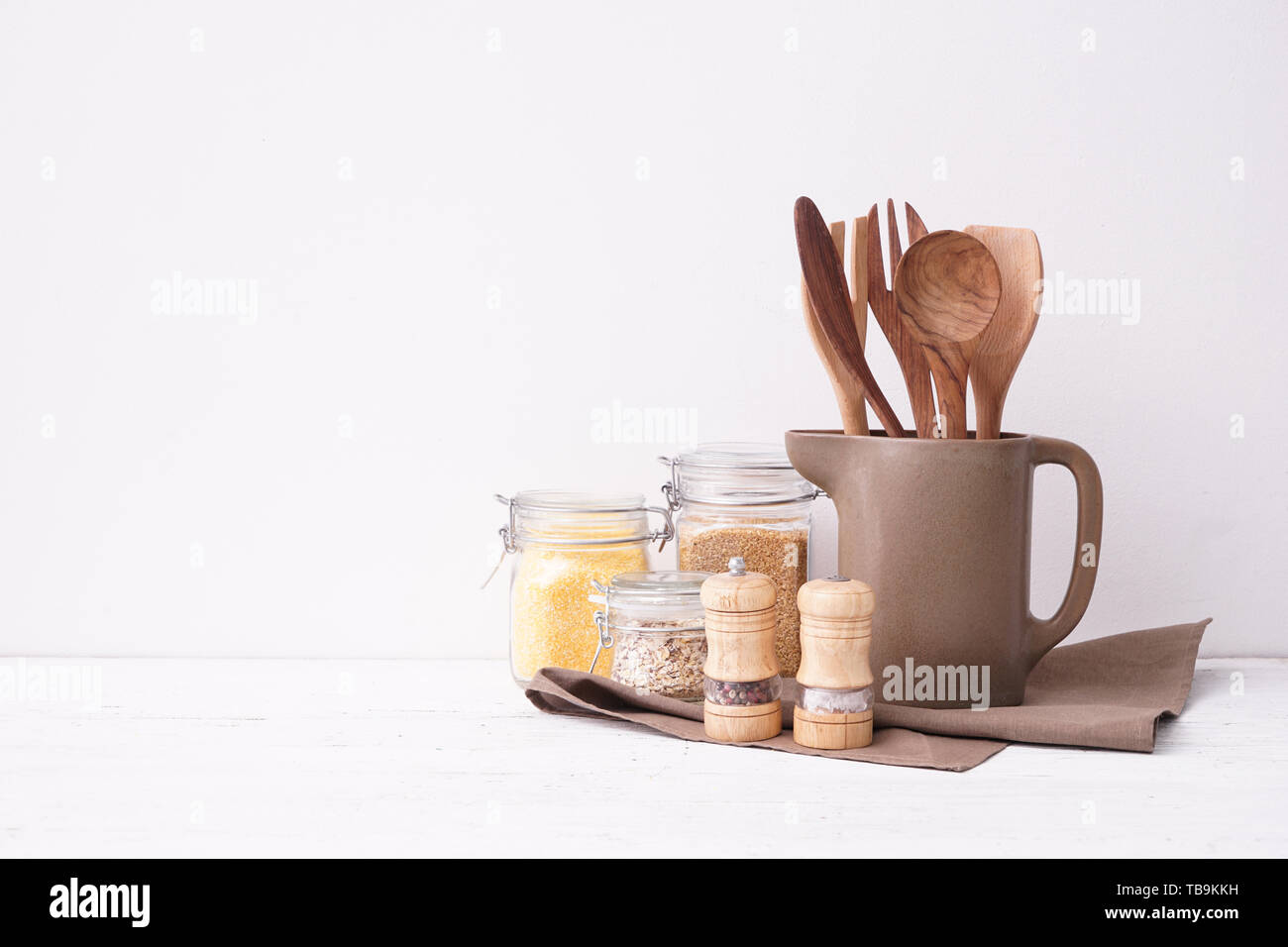 Set di utensili da cucina con semole sul tavolo vicino a muro bianco Foto Stock