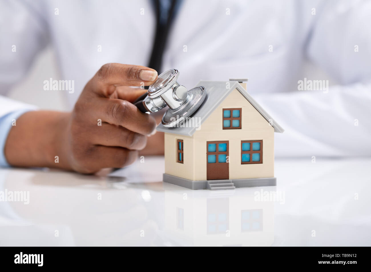 Close-up di un medico di controllo a mano il modello semplice casa con uno stetoscopio Foto Stock