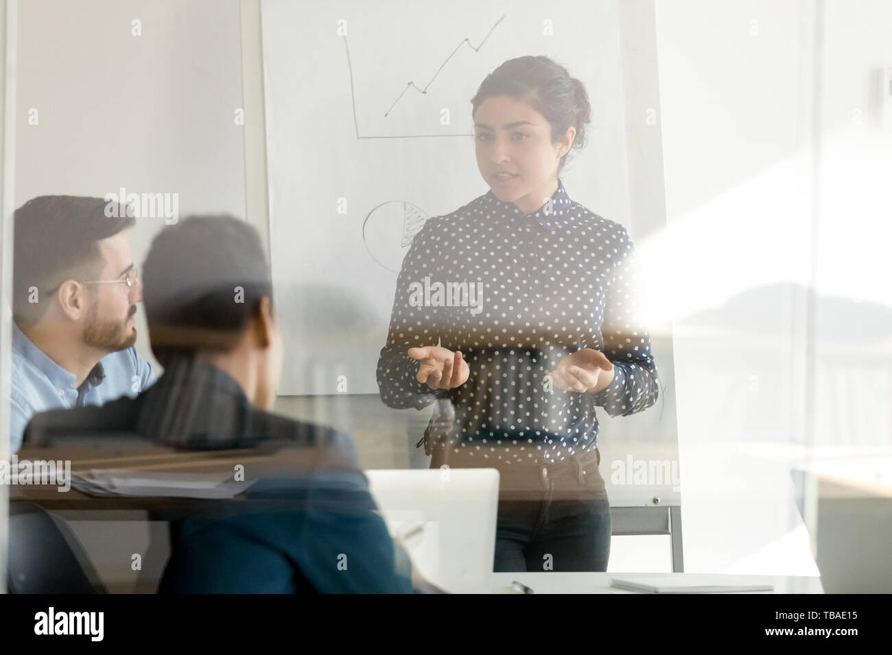 Focalizzato altoparlante femmina brainstorming di parlare con i colleghi in ufficio Foto Stock