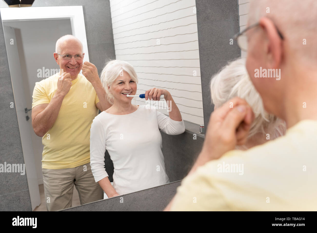 Le persone anziane mediante spazzolatura dei denti e il filo interdentale. La mattina in bagno Foto Stock