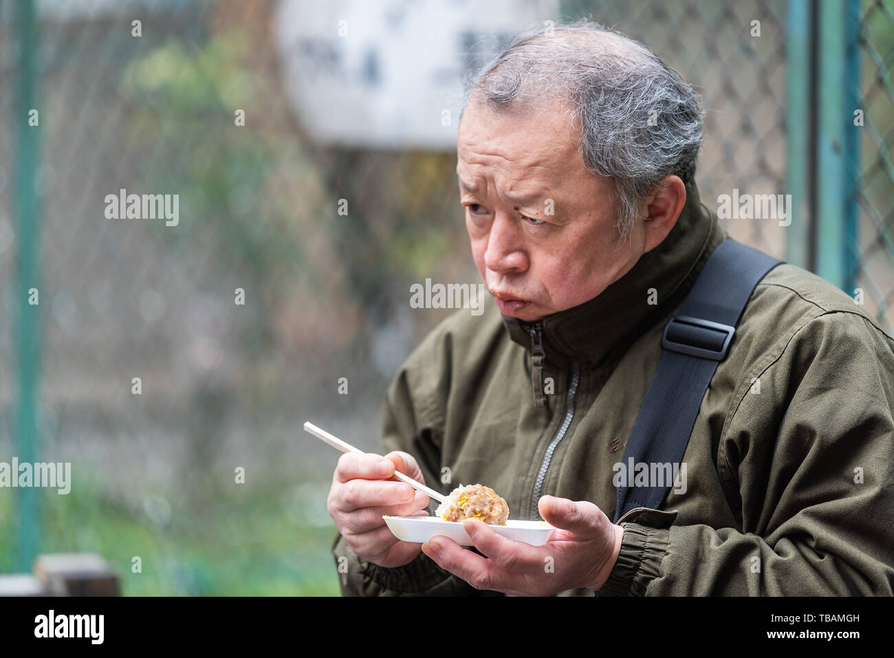 Tokyo, Giappone - 30 Marzo 2019: mercato esterno street di Tsukiji vicino a Ginza con uomo piastra di contenimento di cibo di riso mangiare a sfera Foto Stock