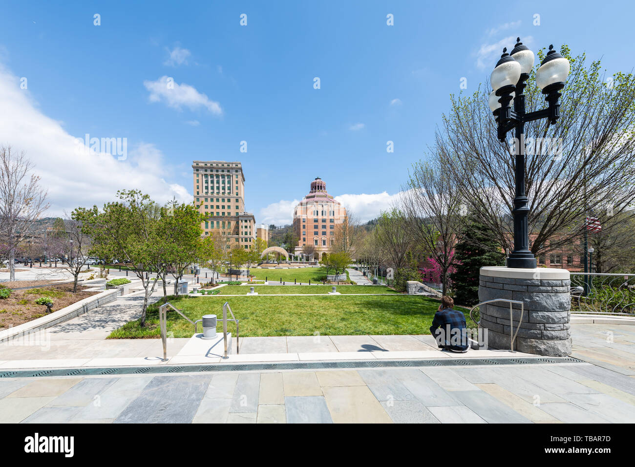 Asheville, Stati Uniti d'America - 19 Aprile 2018: uomo seduto guardando gli edifici courthouse e verde Pack Square Park in hipster North Carolina NC famosa città città Foto Stock