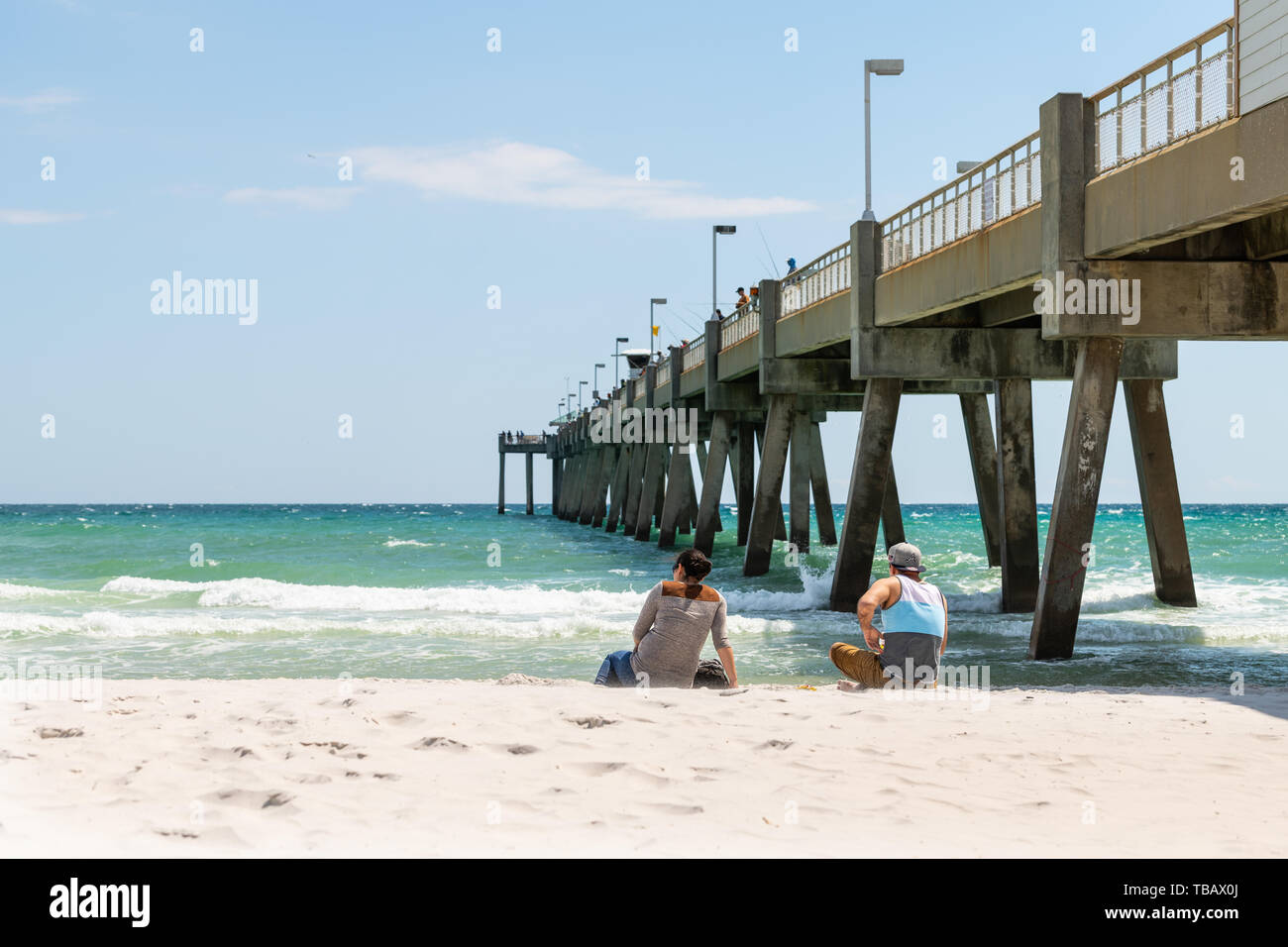 Fort Walton Beach, Stati Uniti - 24 aprile 2018: Persone, coppia sdraiata sulla spiaggia di sabbia al molo di pesca dell'isola di Okaloosa con onde marine oceaniche al Golfo di Me Foto Stock