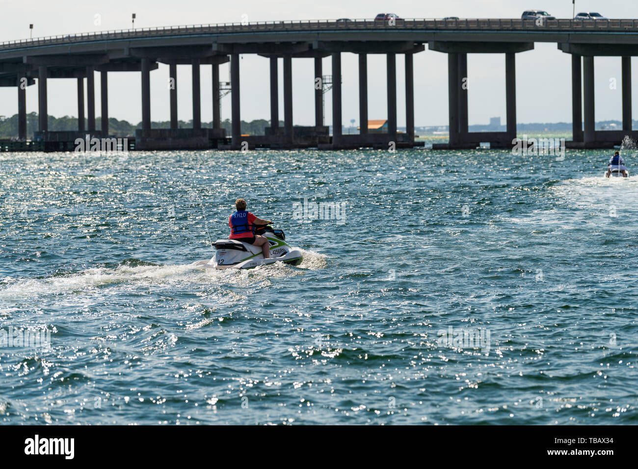 Destin, Stati Uniti d'America - 24 Aprile 2018: due donne sciare sul jet ski in esterni al Golfo del Messico Ocean con vista sulla US Route 98 road bridge in Harborwalk Village, Foto Stock