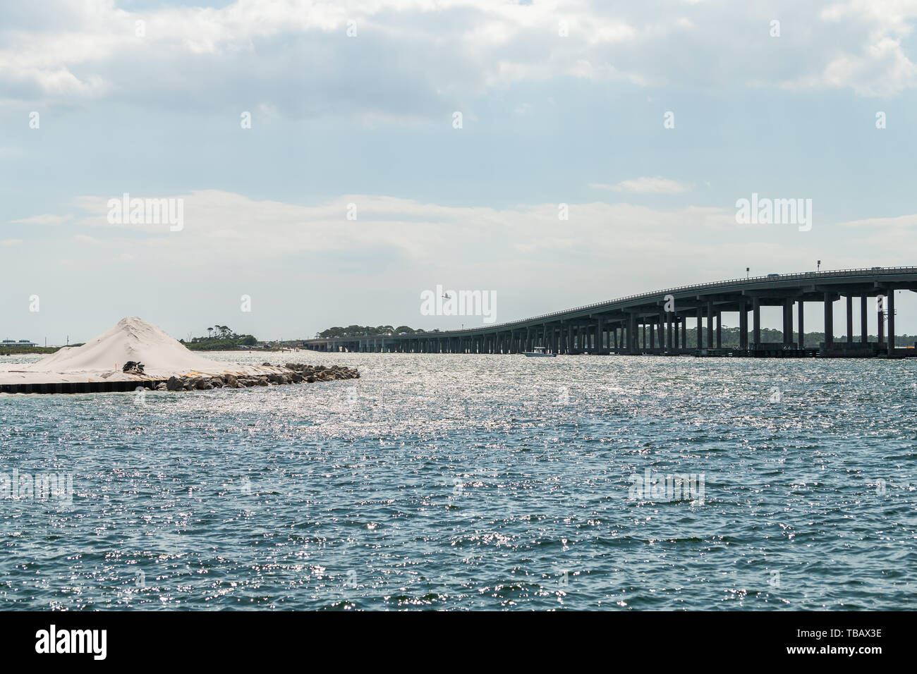 La sabbia bianca isola con sito in costruzione al Golfo del Messico Ocean con vista sulla US Route 98 road bridge in Harborwalk villaggio di Destin, in Florida Panhand Foto Stock