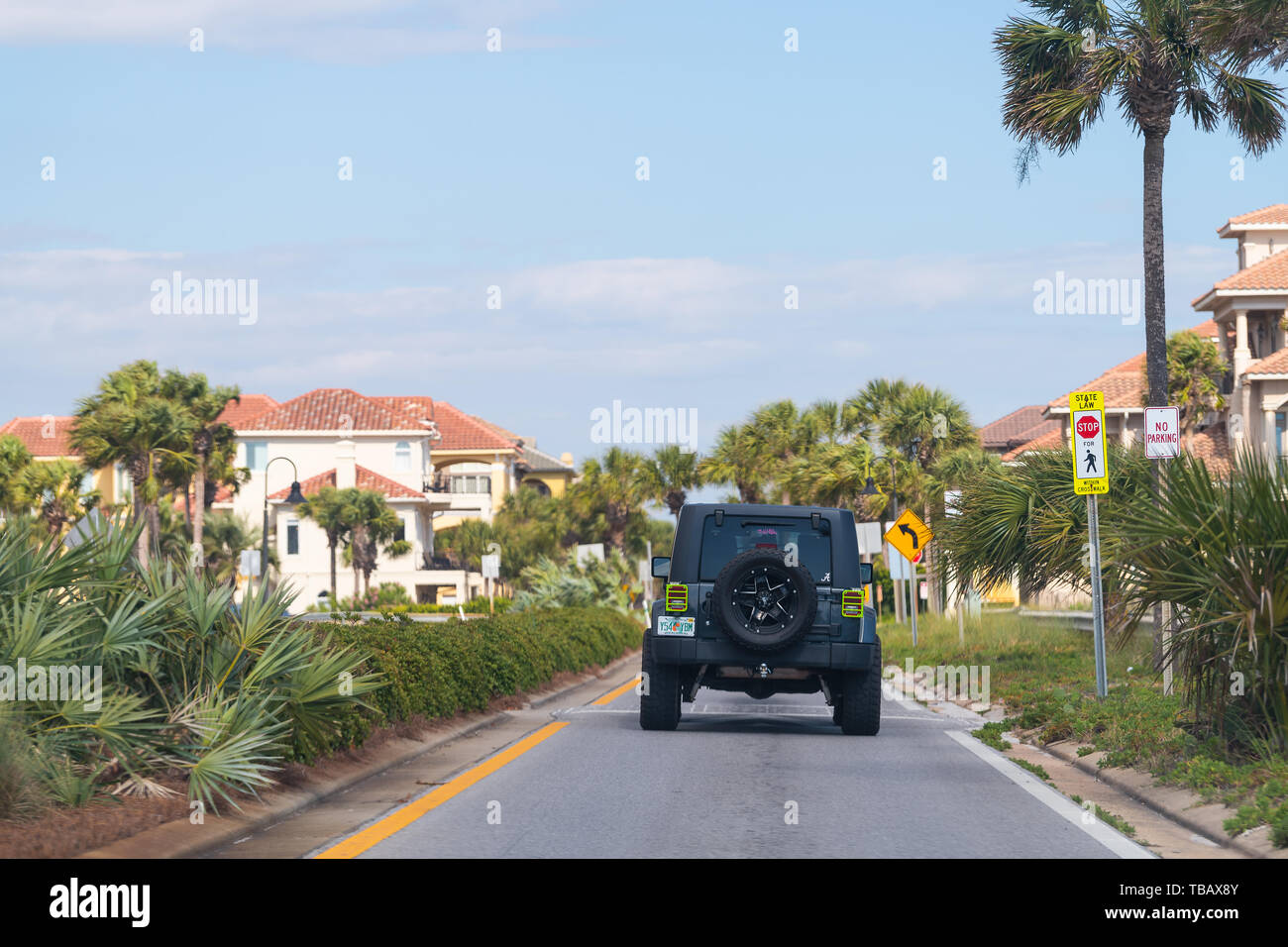 Destin, Stati Uniti d'America - 24 Aprile 2018: Street con auto, pam alberi lungo la strada a Miramar Beach città o paese con stile Spagnolo case in estate giornata soleggiata in Flo Foto Stock