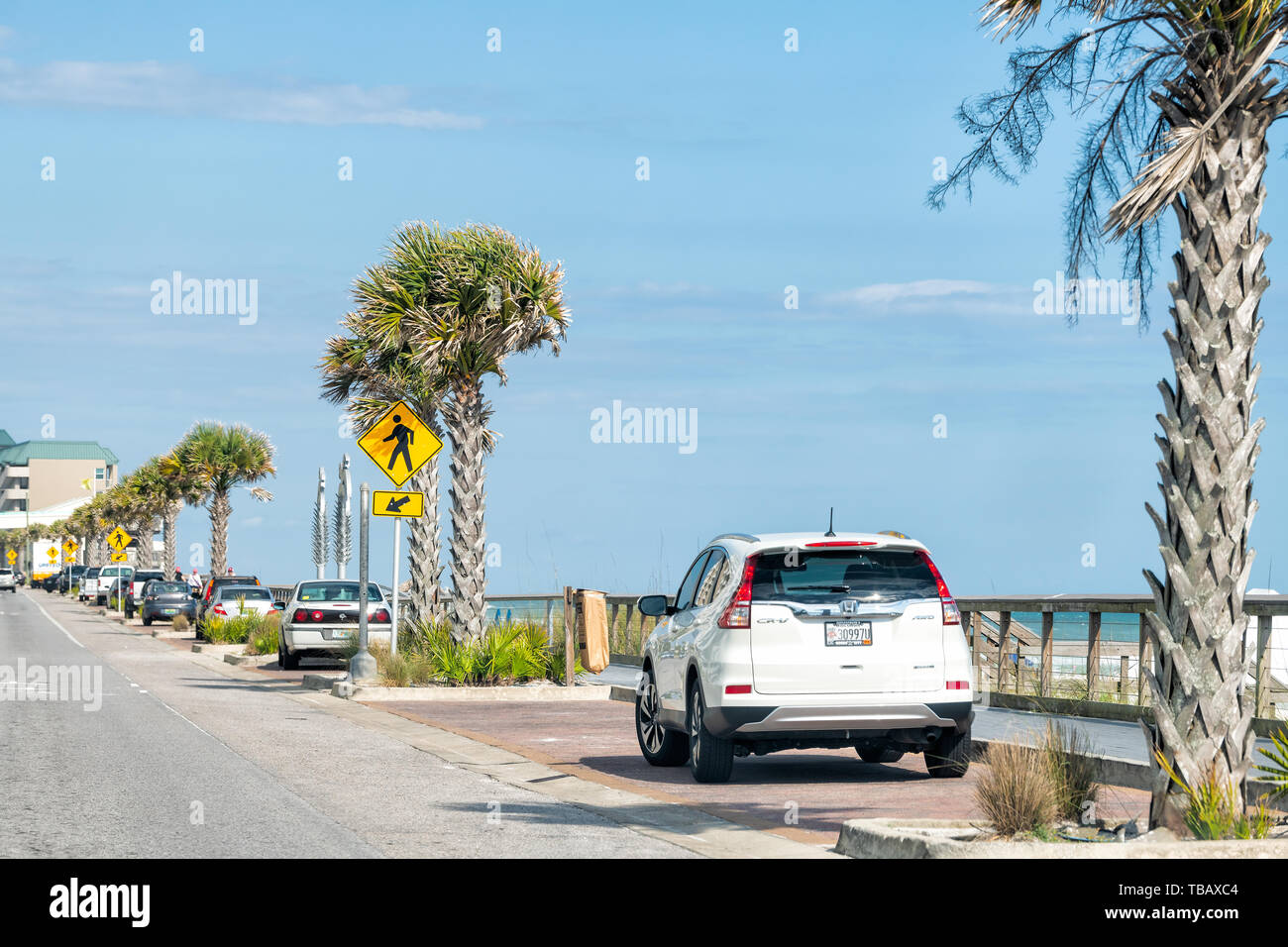 Destin, Stati Uniti d'America - 24 Aprile 2018: Miramar Beach City town strada con un condominio in condominio edifici appartamento dall' oceano lungomare con palme, auto Foto Stock