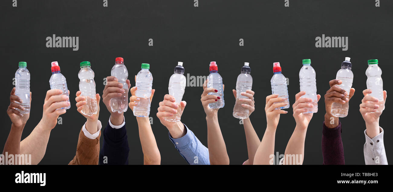 Gruppo di diverse persone che trattengono le bottiglie di acqua in una fila contro lo sfondo di colore verde Foto Stock