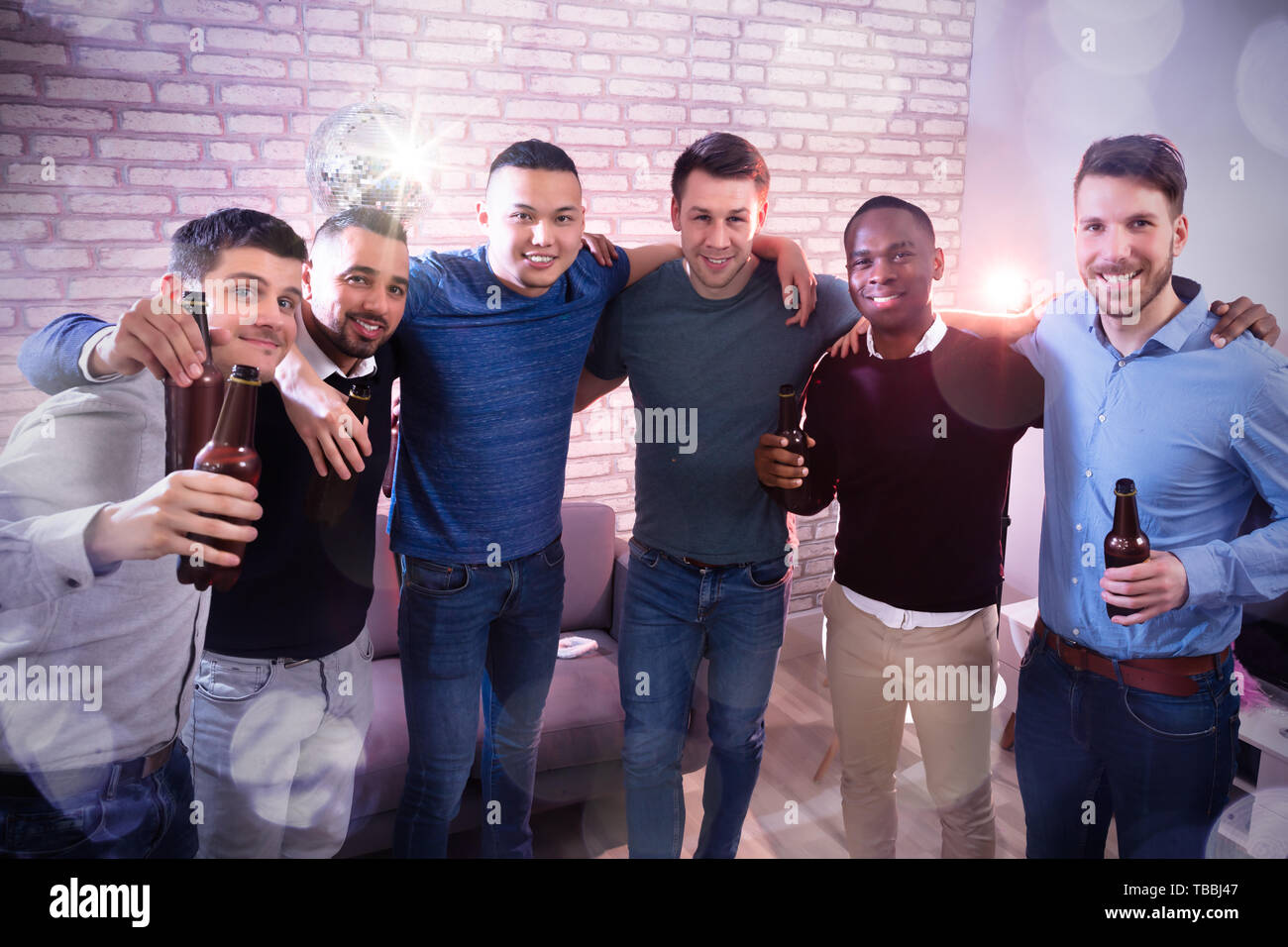 Ritratto di sorridere giovani uomini con le bottiglie di birra guardando la fotocamera in pub Foto Stock