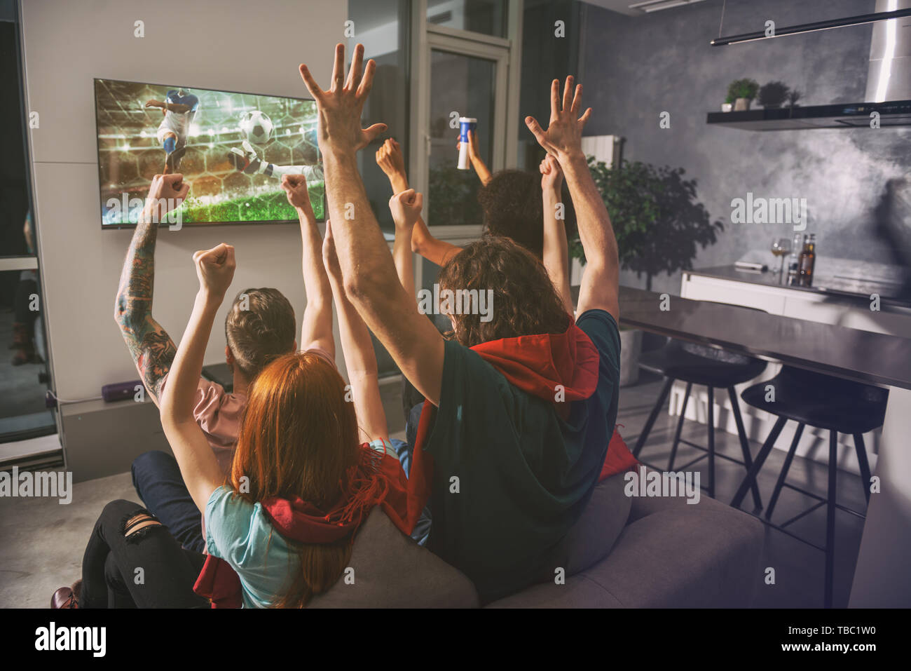 Gruppo di amici guardare la partita insieme sul televisore e rallegratevi Foto Stock