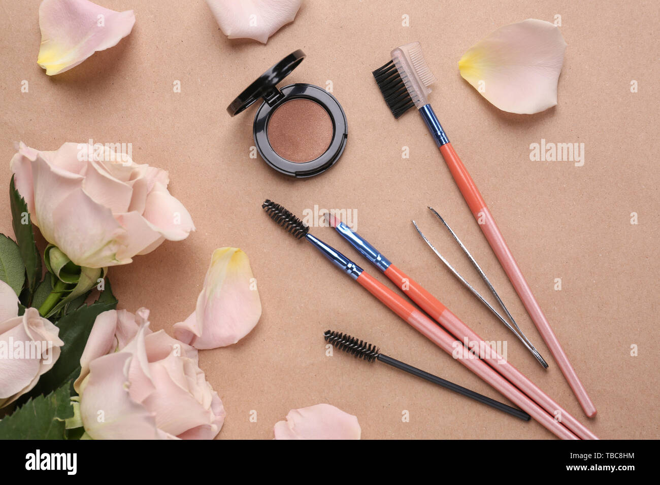 Set di strumenti per la correzione delle sopracciglia e fiori sul colore di sfondo Foto Stock