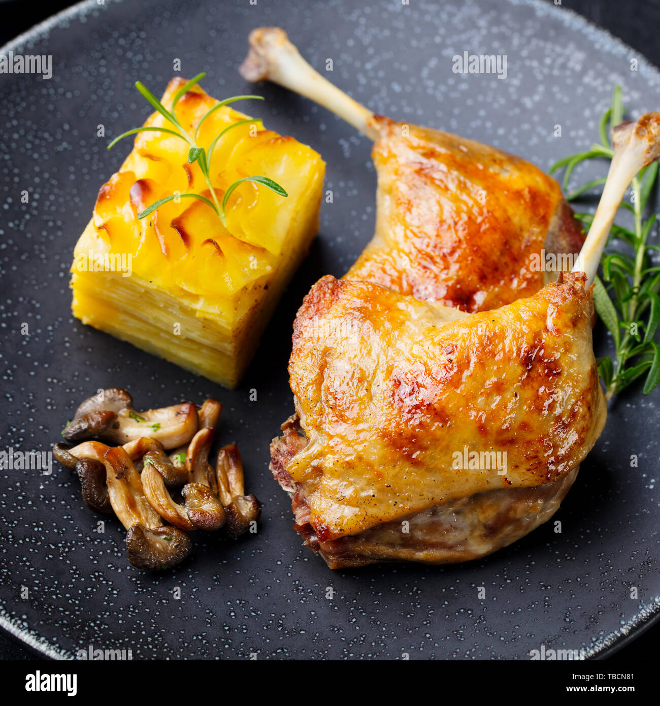 Gambe di Anatra confit con patate gratinate e fungo. Close up. Foto Stock