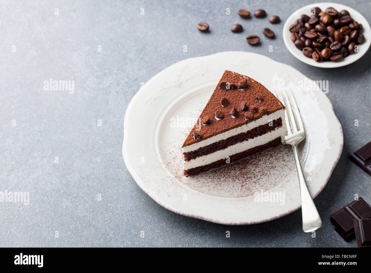 Il tiramisù torta di cioccolato decotaion su una piastra. Grigio pietra dello sfondo. Copia dello spazio. Foto Stock