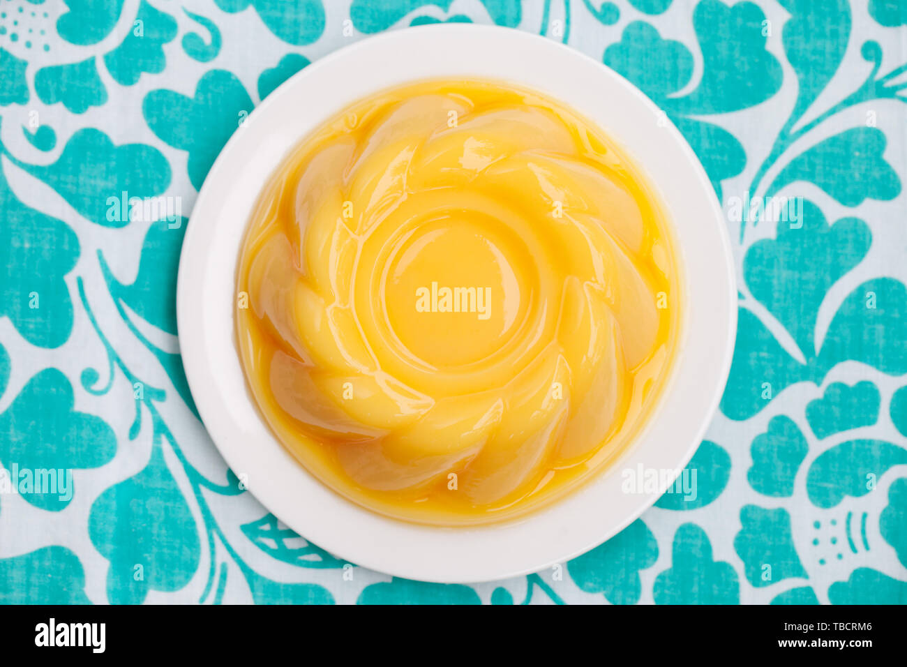 Budino di mango, jelly sulla piastra bianca blu sfondo tessili. Vista dall'alto. Copia dello spazio. Foto Stock