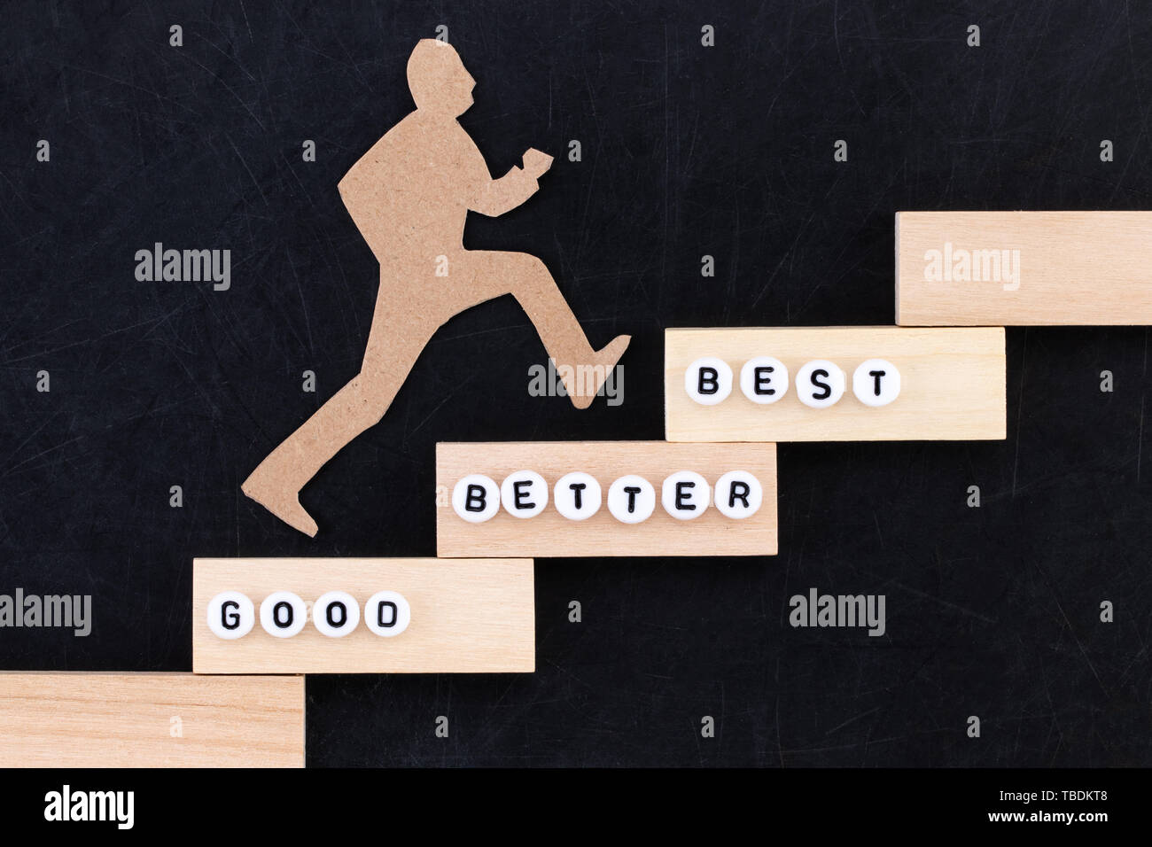 Buona - Migliore - miglior carta uomo salire gli scalini per raggiungere il successo in una immagine concettuale su sfondo nero. Foto Stock