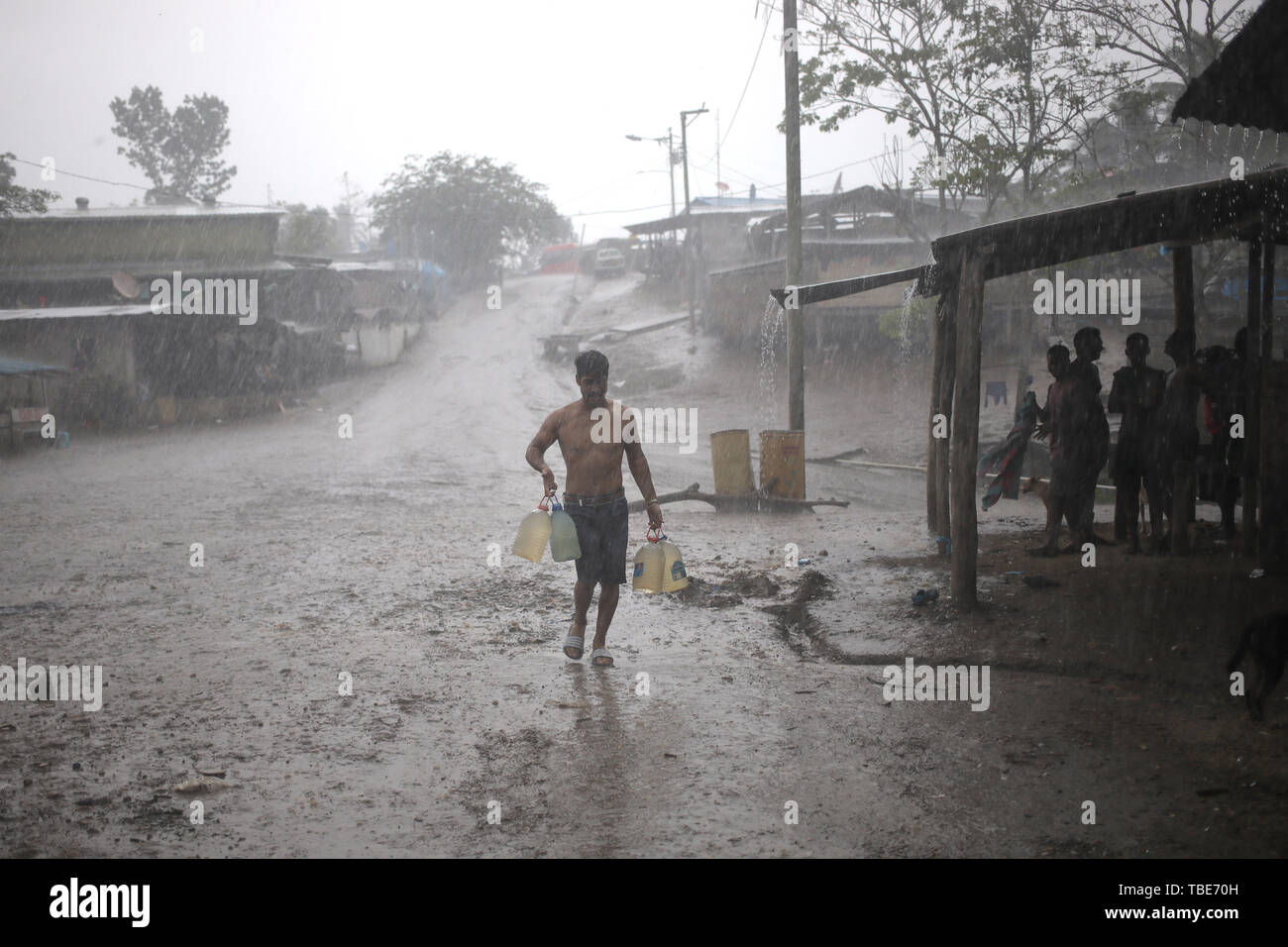 La Penita, Panama. 31 Maggio, 2019. Sotto la pioggia battente, migrante porta acqua potabile taniche ad un magazzino che serve come alloggio per i migranti in Darien la foresta pluviale. Migliaia di migranti provenienti da più di 25 nazioni, principalmente da Haiti, i paesi africani e Cuba, spesso attraversano il Darien la giungla a piedi per diverse settimane sul loro modo attraverso l America del Sud e Centrale per il Messico e infine negli Stati Uniti. Il Darien interrompe il corso lungo la Panamericana, la strada di collegamento di tutto il continente americano. Credito: Mauricio Valenzuela/dpa/Alamy Live News Credito: dpa picture allia Foto Stock