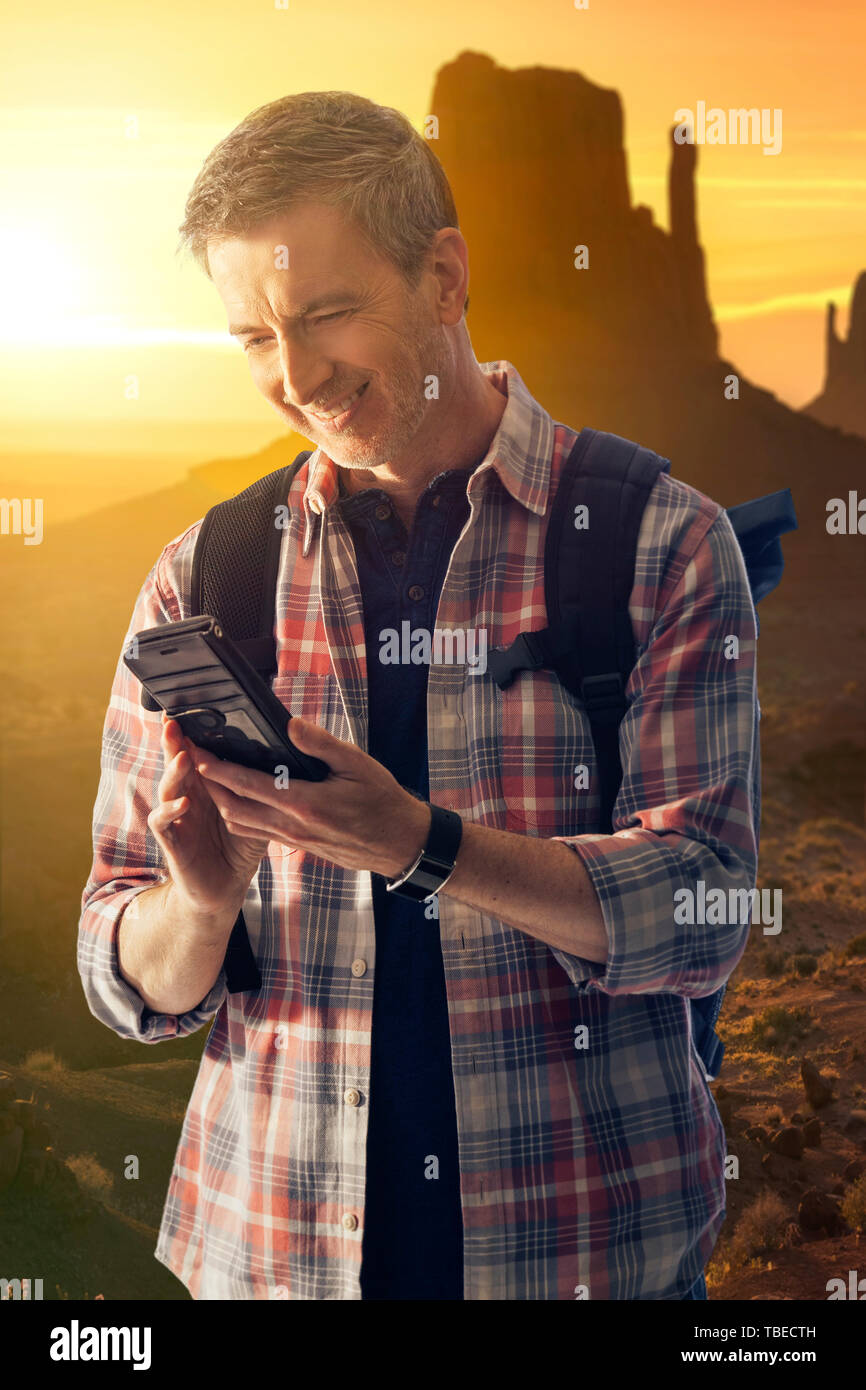 L'uomo escursioni nel deserto e di effettuare una chiamata su un telefono cellulare che è in grado di ottenere la ricezione di rete. Essendo in grado di utilizzare un telefono cellulare è una sopravvivenza Foto Stock