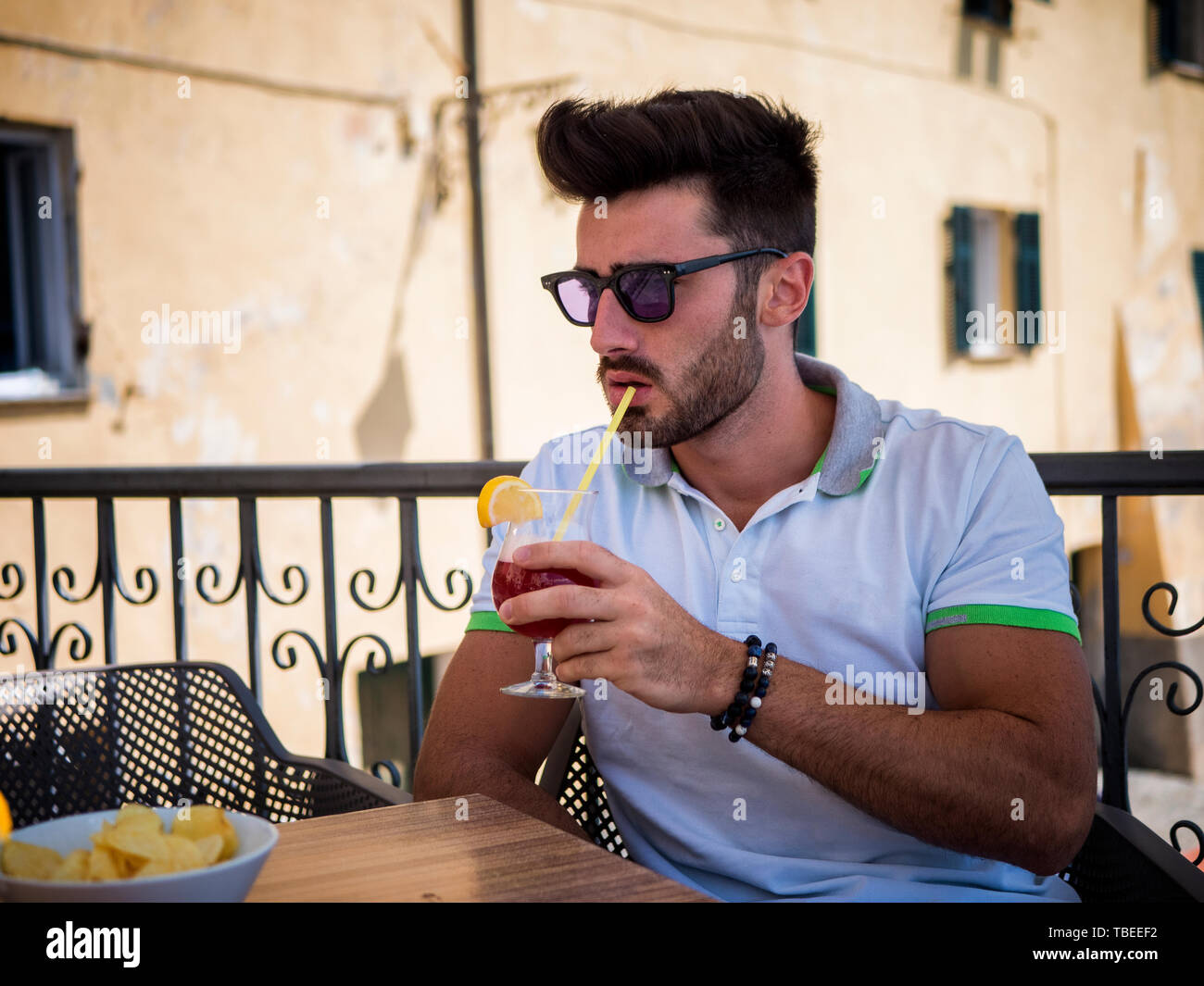 Giovane uomo avente cocktail al bar esterno Foto Stock