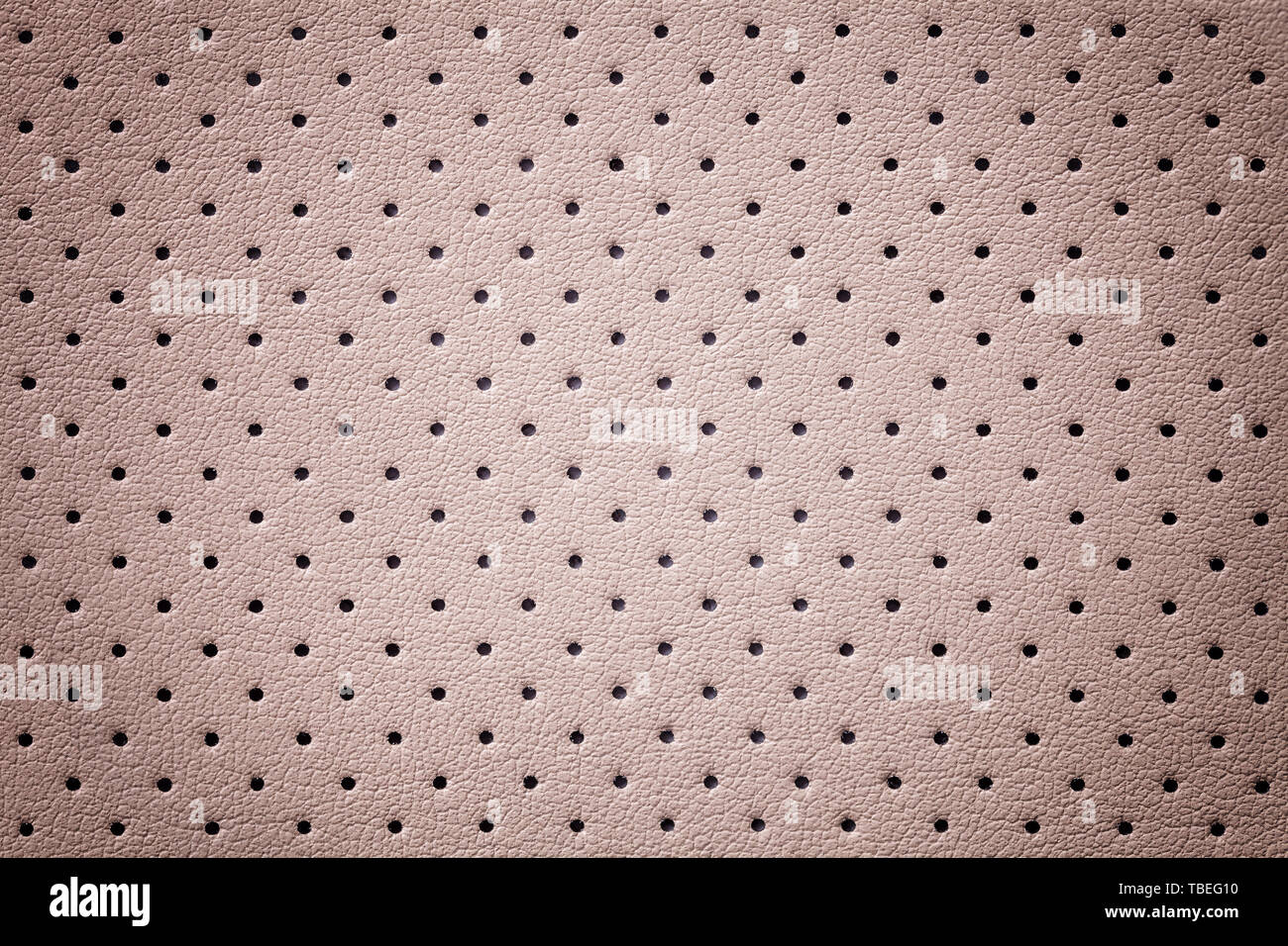Luce perforata in pelle rosa sullo sfondo di tessitura con telaio a gradiente, primo piano. Oro rose sfondo dalla pelle antirughe, la struttura di tessuto con vignet Foto Stock