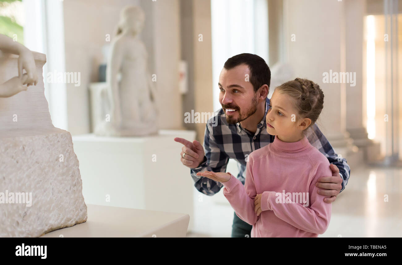 Uomo positivo e piccola ragazza spiegazione antiche statue in museo Foto Stock