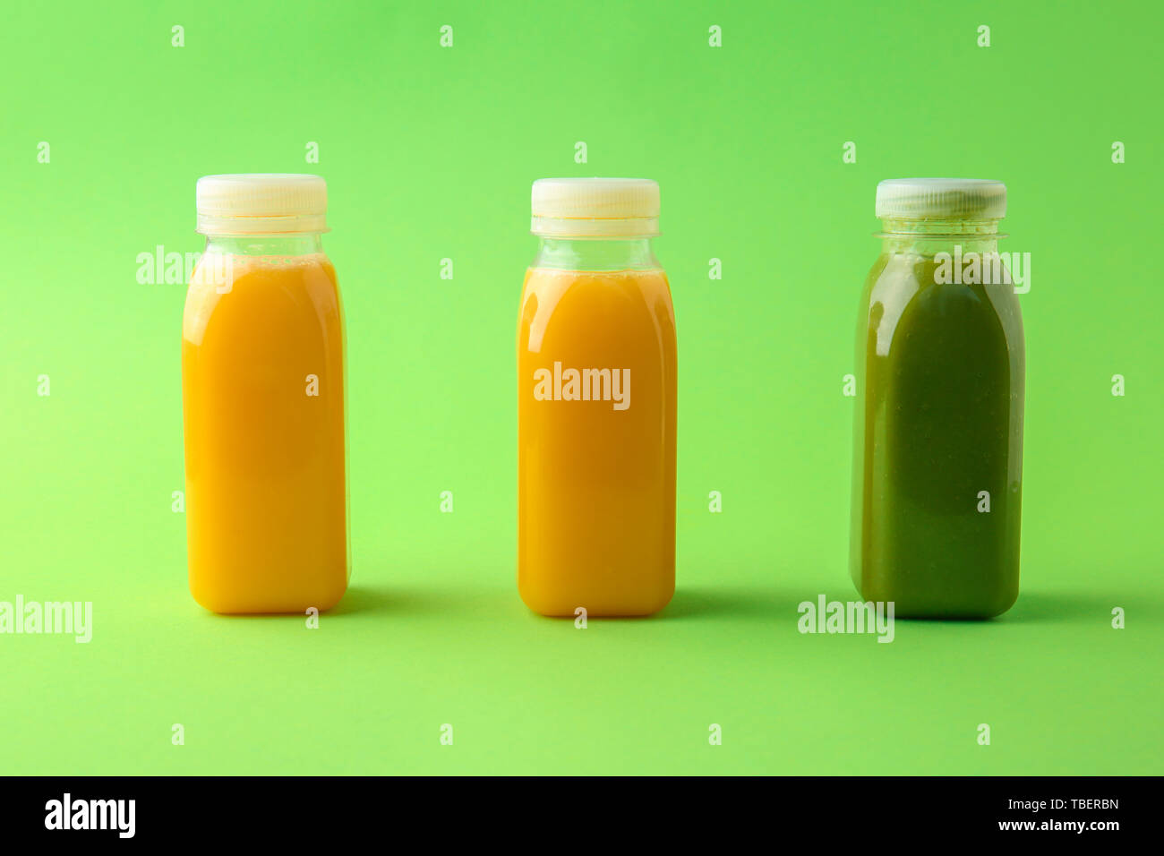 Bottiglia di succo verde tra quelli di colore giallo su sfondo colorato. Concetto di unicità Foto Stock