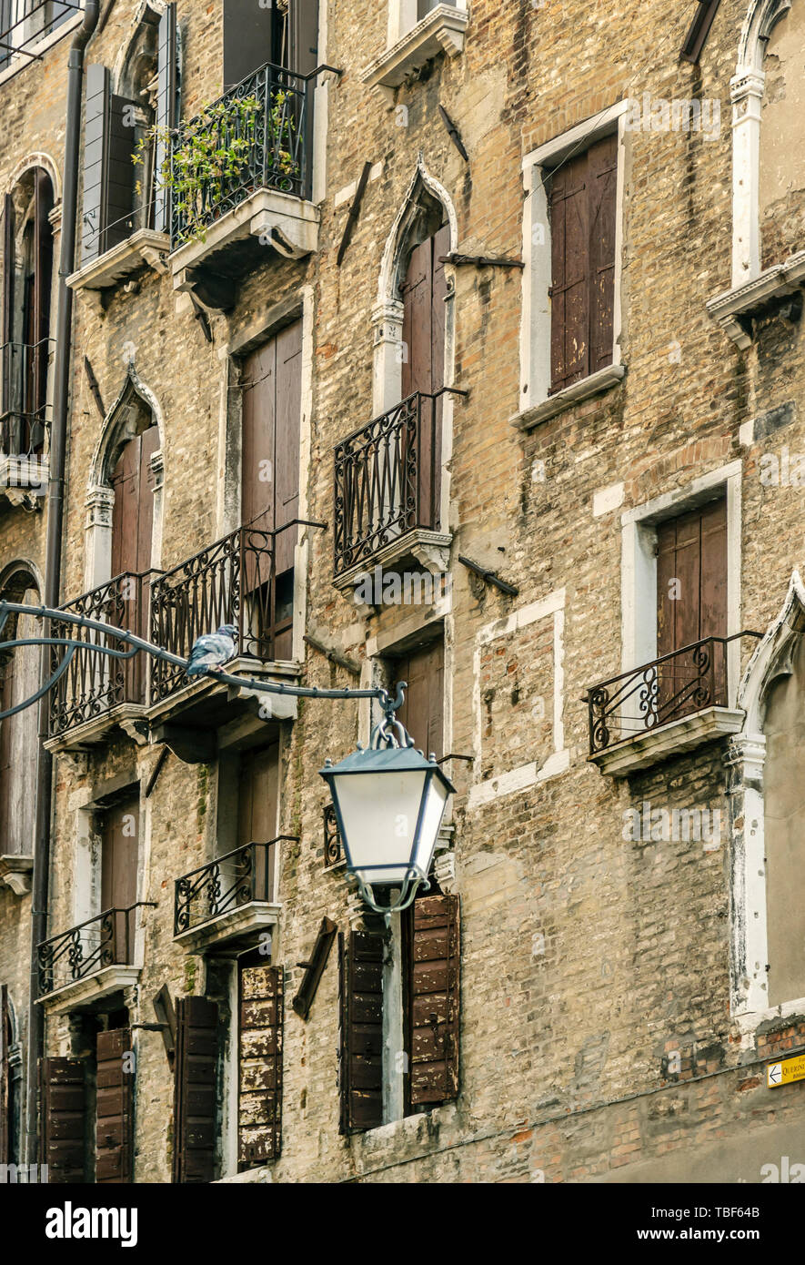 Venezia, Italia - 25 August, 2018: frammento di un veneziano di casa in mattoni con finestre autentica e fiori in vaso su di essi Foto Stock
