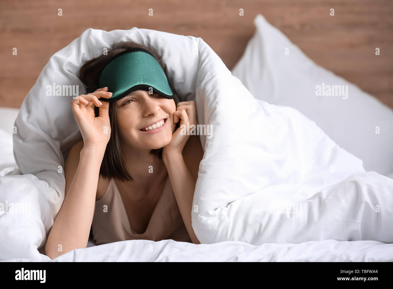 Giovane donna con maschera di dormire nel letto Foto Stock