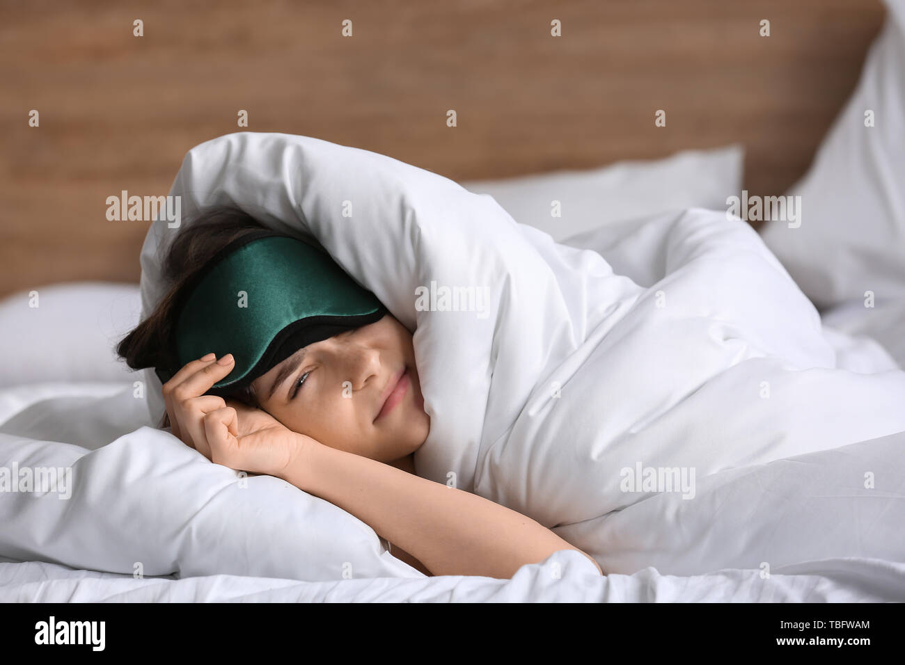 Assonnato giovane donna con maschera a letto Foto Stock