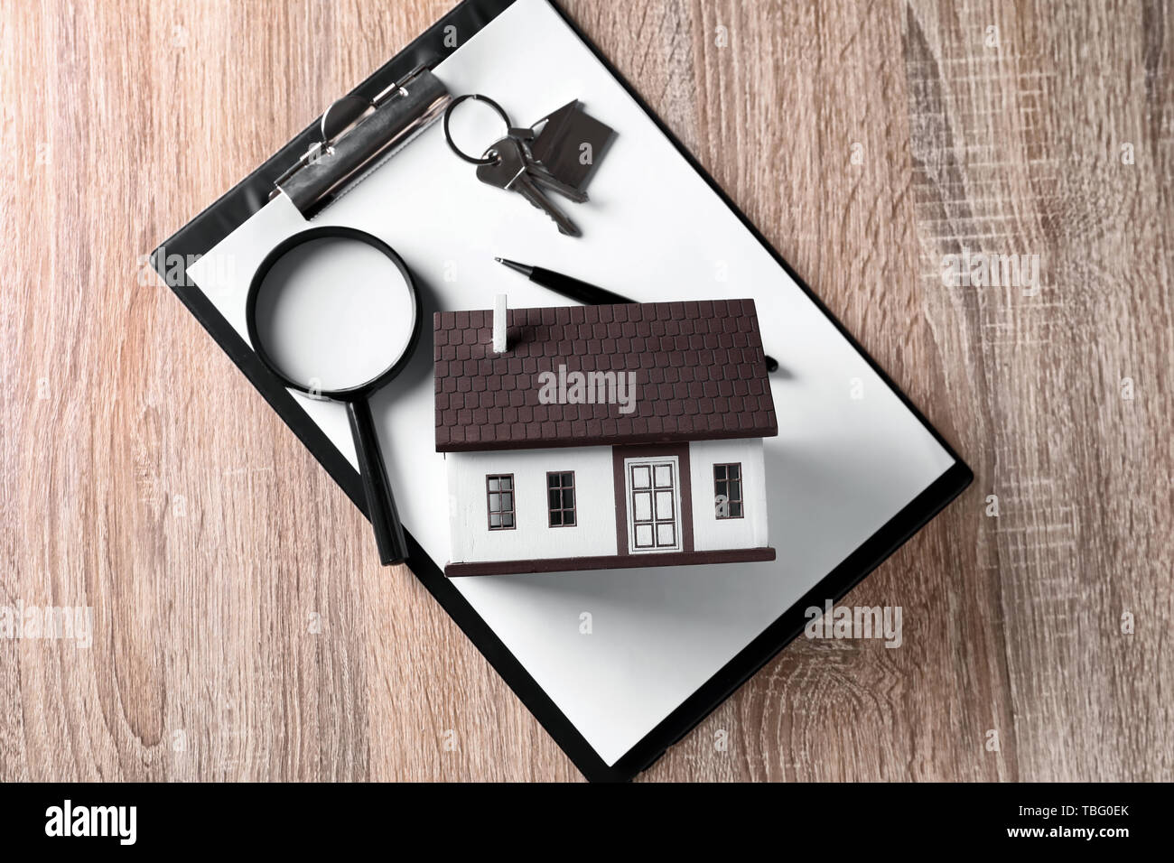 Modello di casa con la chiave, Magnifier e appunti su un tavolo di legno. Concetto di terremoto Foto Stock